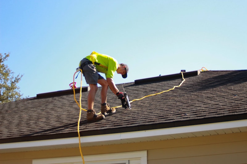 Roofer nailing shingles on a residential roof